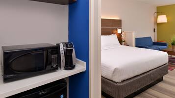 A hotel room with a microwave, coffee maker, and a bed.