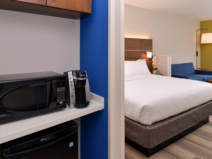 A hotel room with a microwave, coffee maker, and a bed.