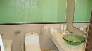 Un baño con inodoro, bidé y lavamanos de vidrio.