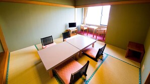 Una habitación tradicional japonesa con suelo de tatami, una mesa baja con cojines y un televisor.