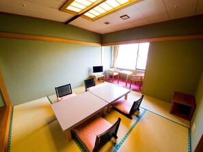A traditional Japanese-style room with tatami flooring, a low table with cushions, and a television. - Naruto Grand Hotel (Naruto)