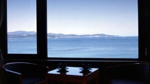 A room with a large window overlooking a coastal view. - Naruto Grand Hotel (Naruto)