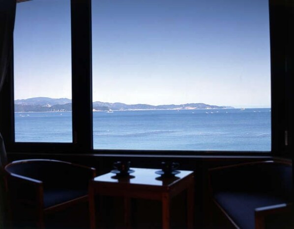 A room with a large window overlooking a coastal view. - Naruto Grand Hotel (Naruto)