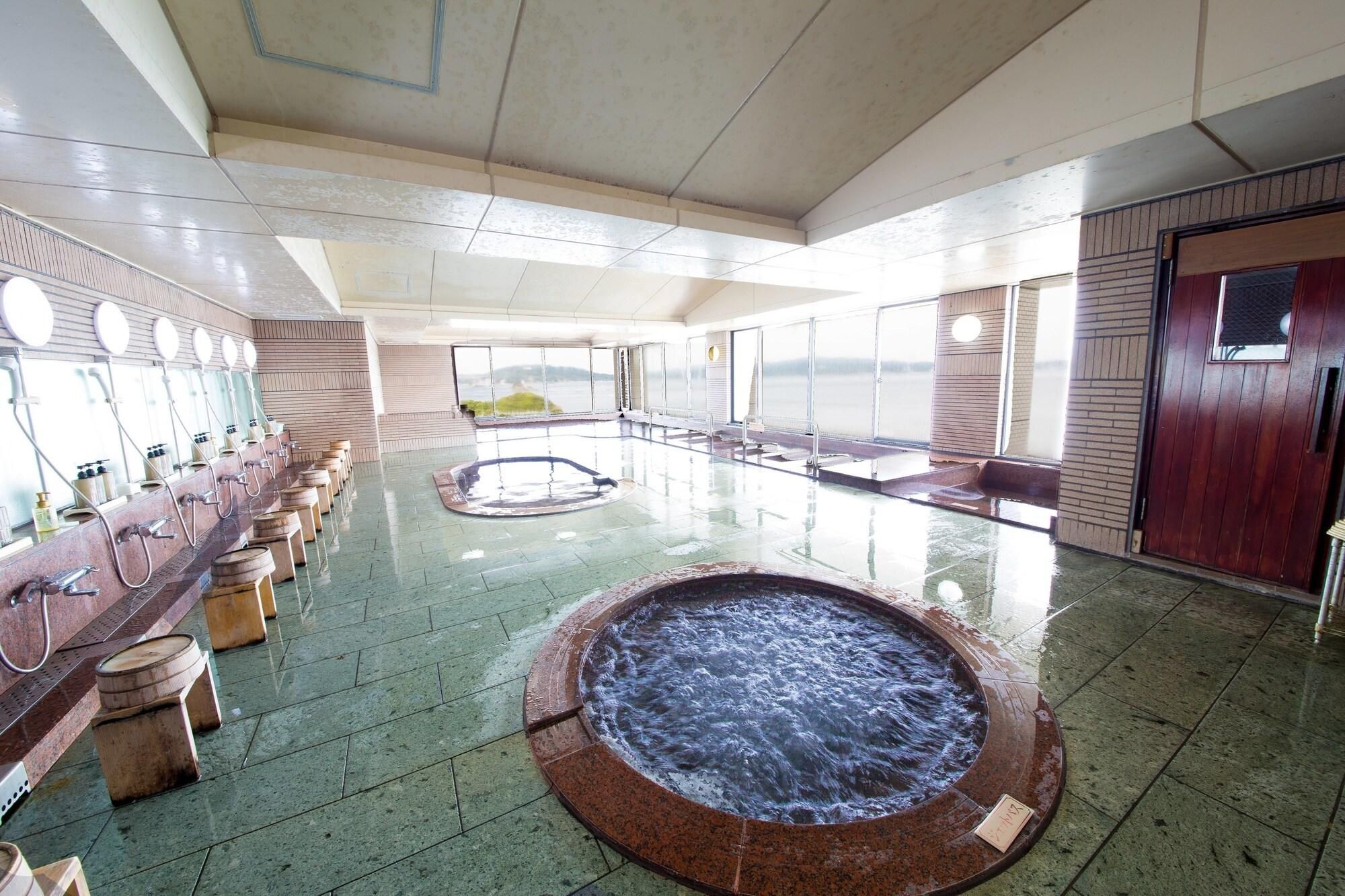 A large indoor pool area with multiple shower stations and a central hot tub.