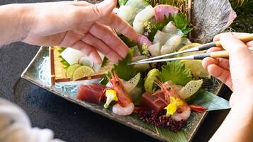 Una bandeja de sushi con diversos ingredientes y un par de palillos.