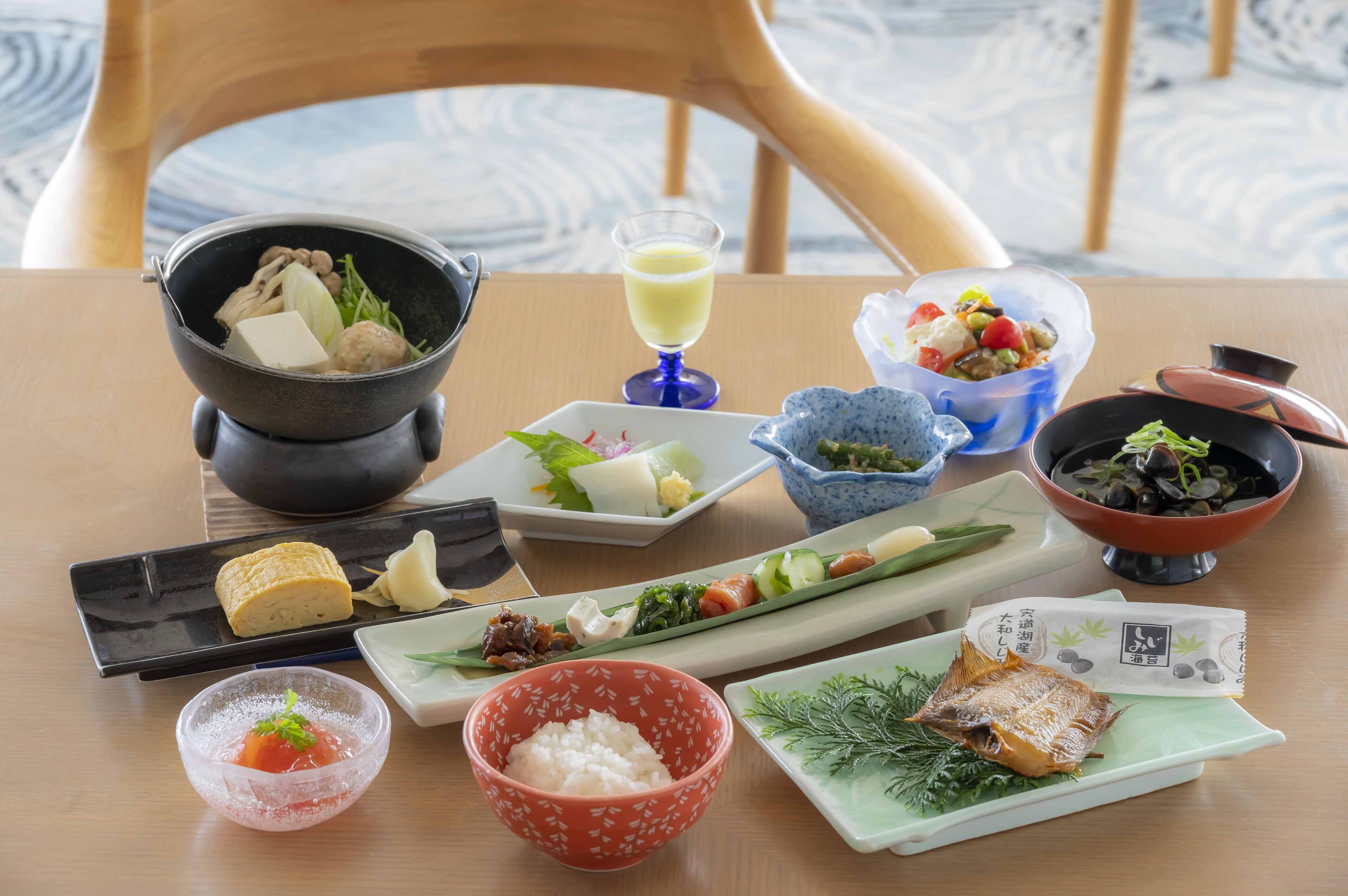 A table set with various Japanese dishes including sushi, sashimi, and a bowl of rice.