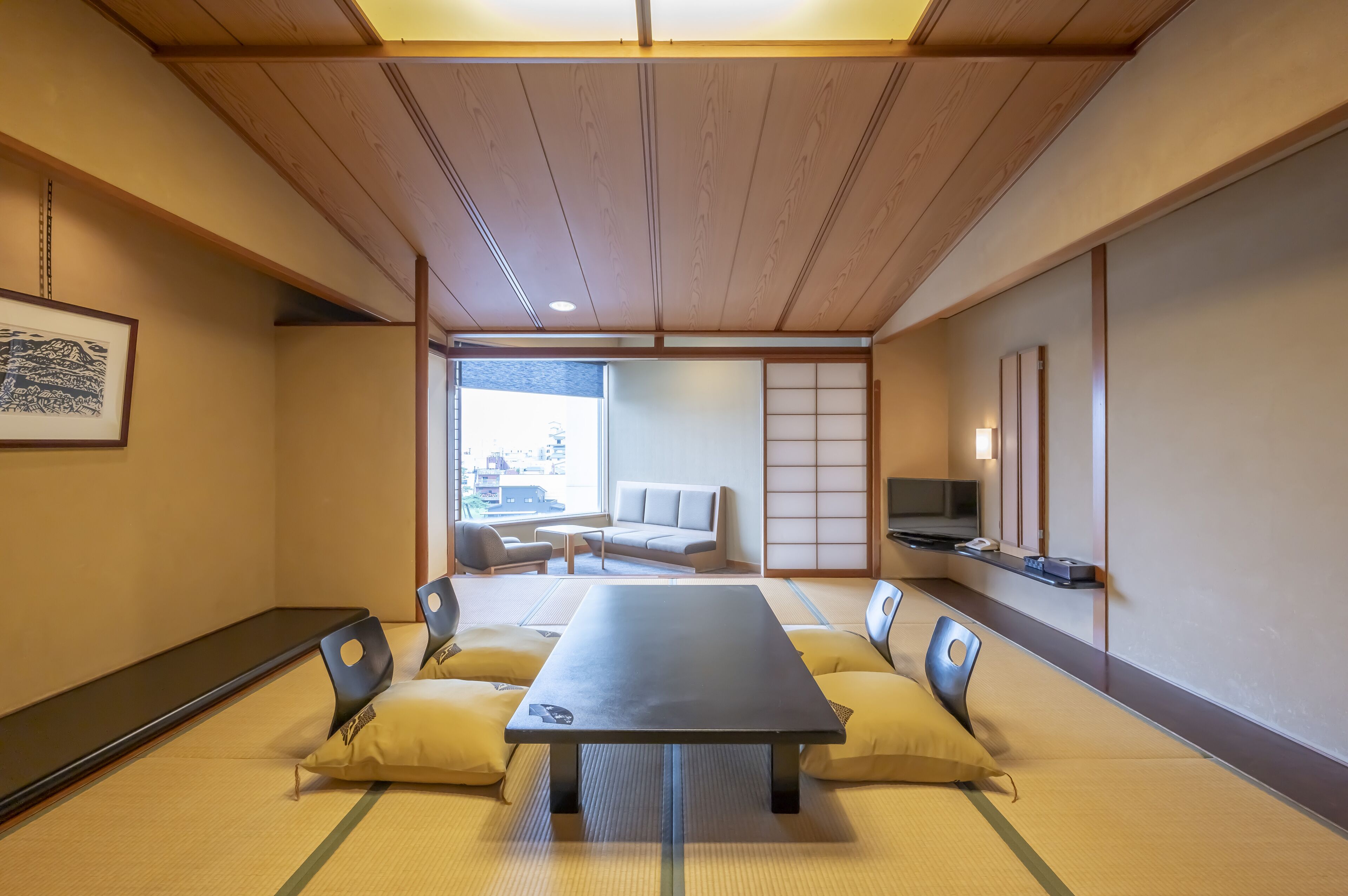 A traditional Japanese room with tatami flooring, a low table, cushions, a sofa, and a sliding door.
