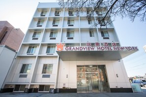 Un hotel amb una façana moderna, diversos pisos i un cartell ben visible del Grandview Hotel New York.