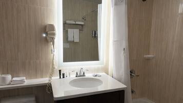 A modern bathroom with a large mirror, a sink, a toilet, and a bathtub.