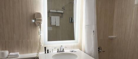 A modern bathroom with a large mirror, a sink, a toilet, and a bathtub.