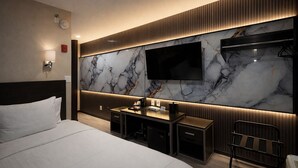 A modern hotel room with a large bed, a desk with a flat-screen TV, and a marble wall. - Grandview Hotel New York (Flushing)