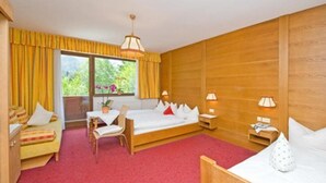 A hotel room with a wooden bed, a wooden desk, a chair, and a window with curtains.