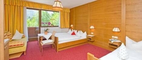 A hotel room with a wooden bed, a wooden desk, a chair, and a window with curtains.