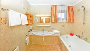 A bathroom with a bathtub, sink, and mirror.