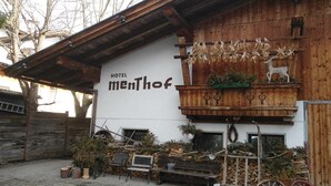 A rustic wooden building with a sign reading "Hotel MenThof".