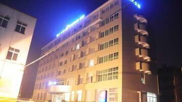A multi-story hotel with a flat facade, multiple windows, and a sign indicating a business or hotel name.