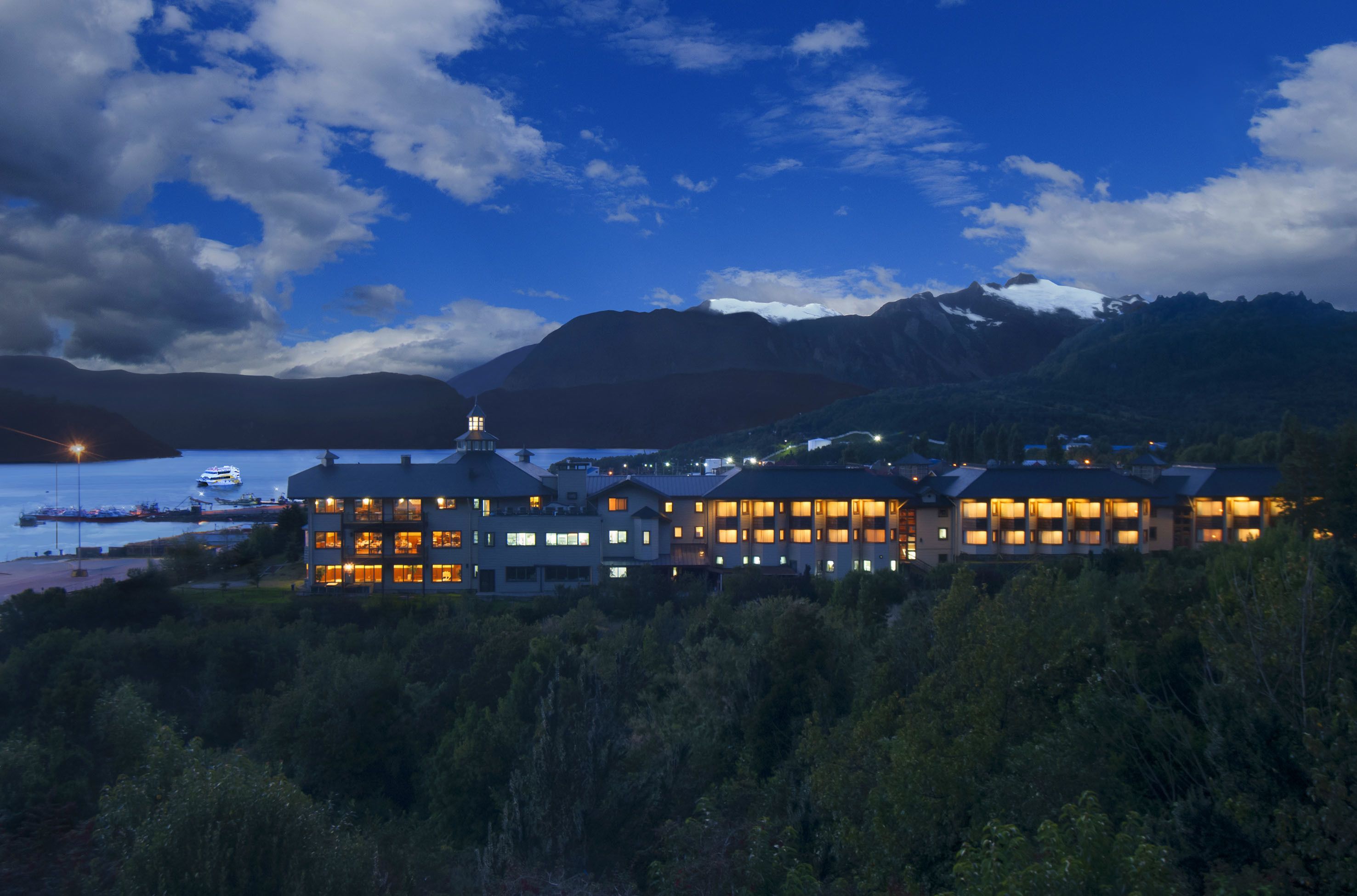 Un grand hôtel composé de plusieurs bâtiments, avec un lac et des montagnes en arrière-plan.