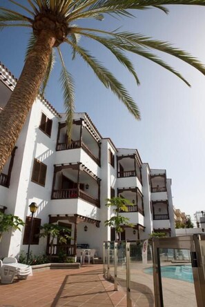 A multi-story building with balconies, a swimming pool, and outdoor seating. - Alsol Las Orquideas (San Bartolomé de Tirajana)