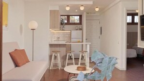 A modern living room with a sofa, a coffee table with a vase, and a kitchen area with stools and a dining table. - Alsol Las Orquideas (San Bartolomé de Tirajana)