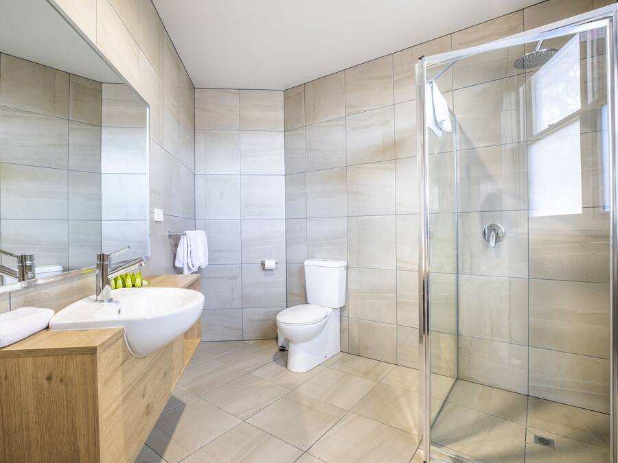 A modern bathroom with a glass-enclosed shower, a wooden vanity, and a large mirror.