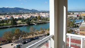 Varanda com vista para um rio, uma cidade e montanhas ao longe.