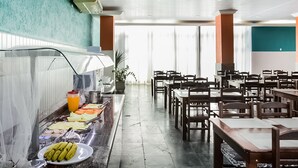 A buffet area with a variety of food items, including fruits and vegetables, and a seating area with tables and chairs. - Hotel InterAmericana (Americana)
