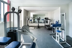 A modern gym with various exercise machines, a treadmill, and a mirrored wall. - Hotel InterAmericana (Americana)