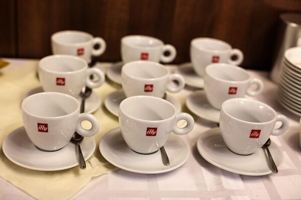 Una mesa con varias tazas y platillos blancos, cada uno con una cuchara y un logotipo.