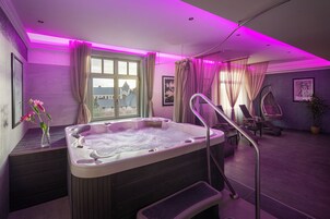 Un moderno cuarto de spa con hidromasaje, una ventana con cortinas, una silla colgante y una planta en maceta.