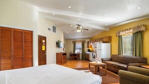 A spacious room with a bed, a sofa, a dining area, and a kitchen. - Roundhouse Resort (Pinetop)
