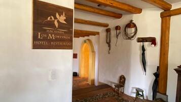 Un pasillo con techo de madera, un letrero que dice 'Hacienda Los Mortinos Hotel - Restaurant' y un piso con diseño.
