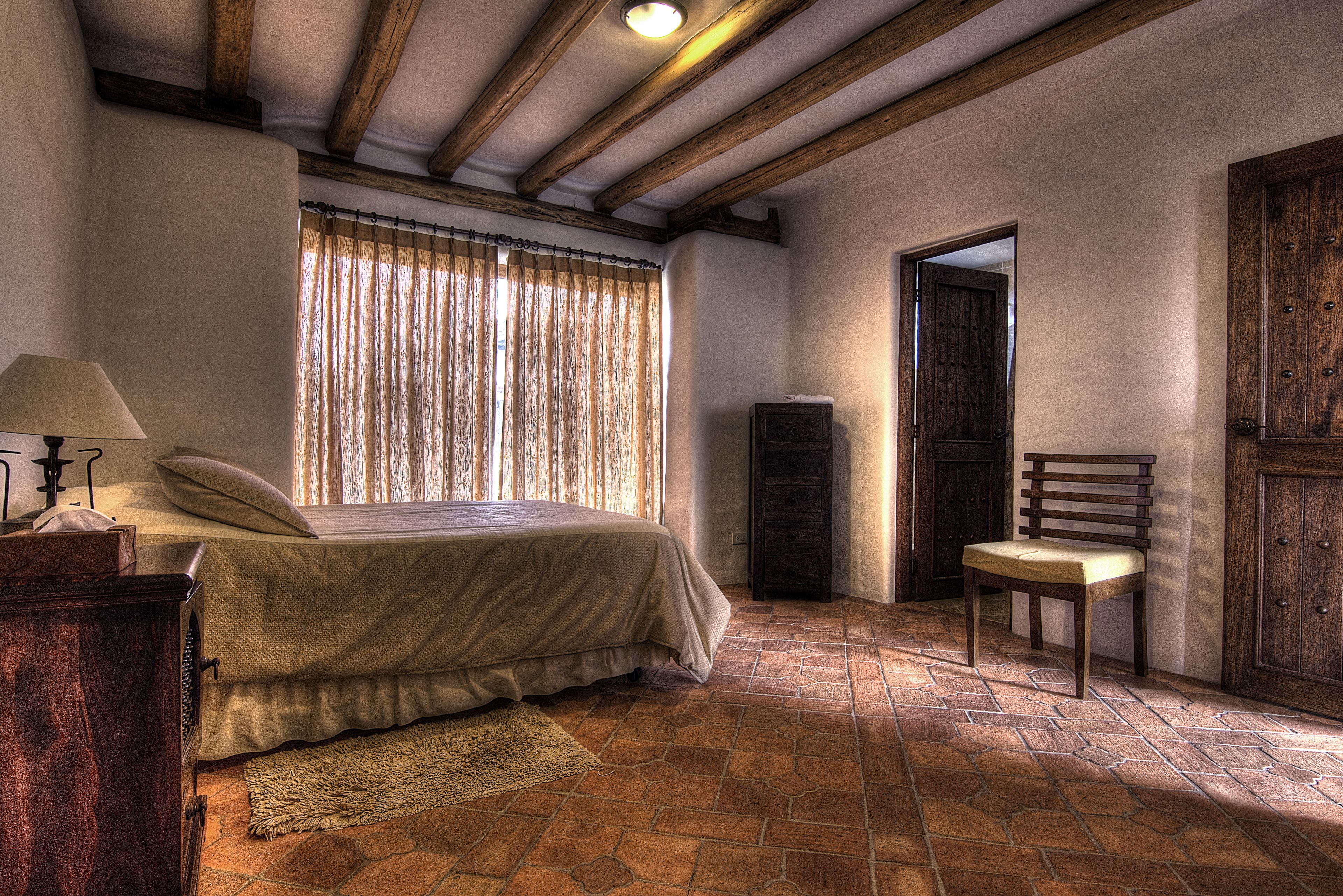 Une chambre à coucher avec un lit, une chaise, une armoire en bois et une lampe.