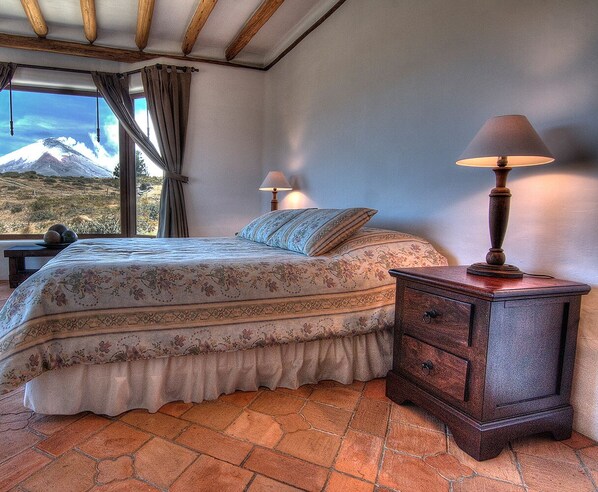 Un dormitorio con una cama, dos lámparas de noche, una mesita de noche y vistas a la montaña.