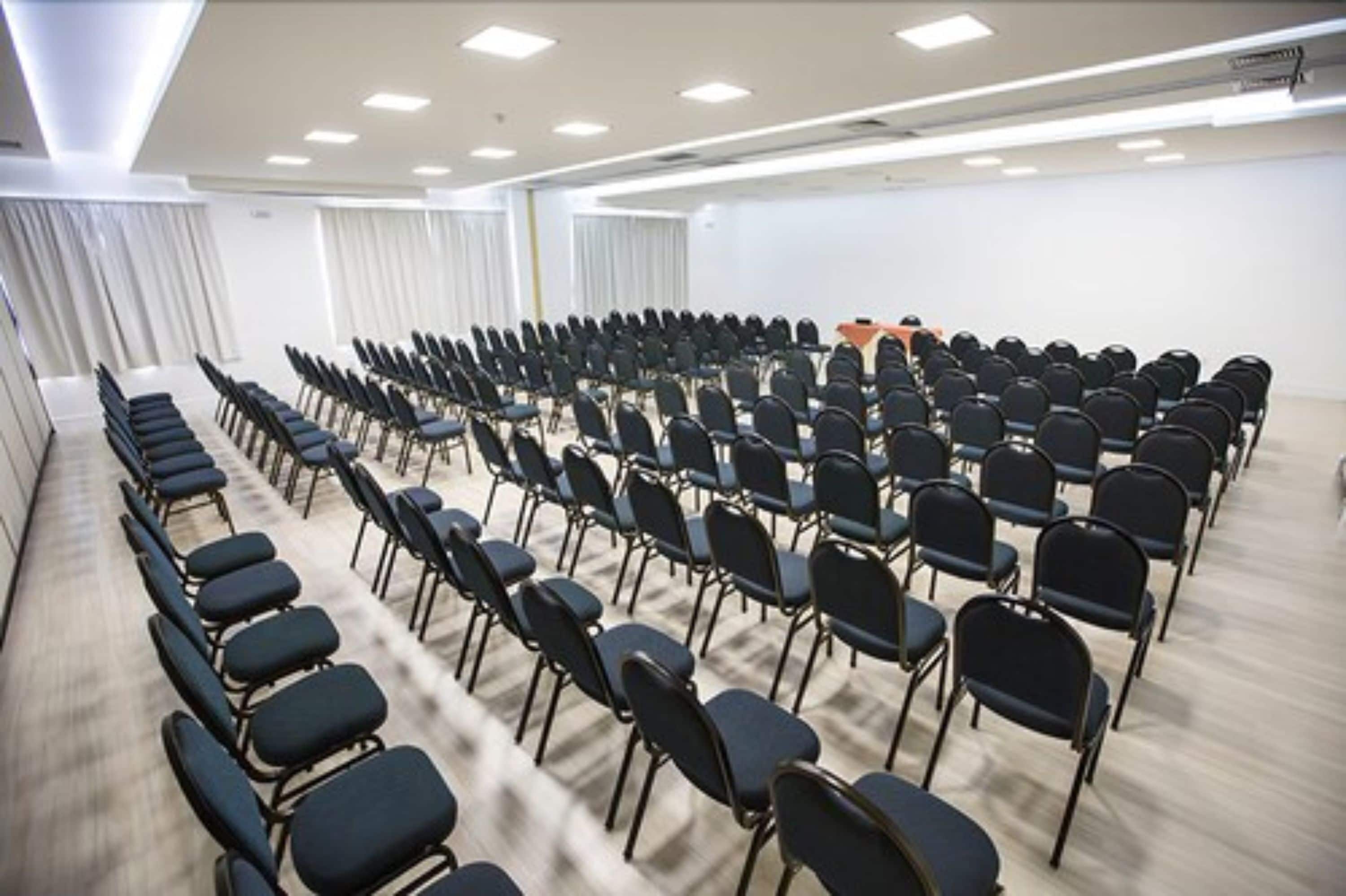 A conference room with rows of chairs, a podium, and a whiteboard.