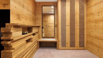 A wooden interior with a bench, a mirror, and a wardrobe.