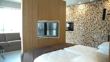 Quarto de hotel moderno com parede revestida de madeira, uma televisão montada e uma parede única feita de troncos.