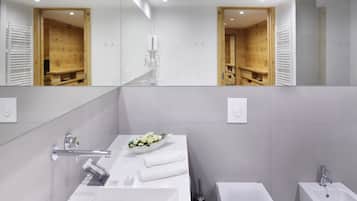 Un baño moderno con un espejo grande, un lavamanos blanco, una bañera y una zona de ducha.