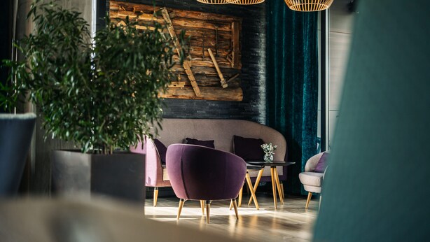Un interior moderno con una pared de madera, sillas moradas y un sofá negro.