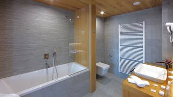 Ein modernes Badezimmer mit einer freistehenden Badewanne, einer Toilette und einem Waschtisch mit Becken und Handtuch.