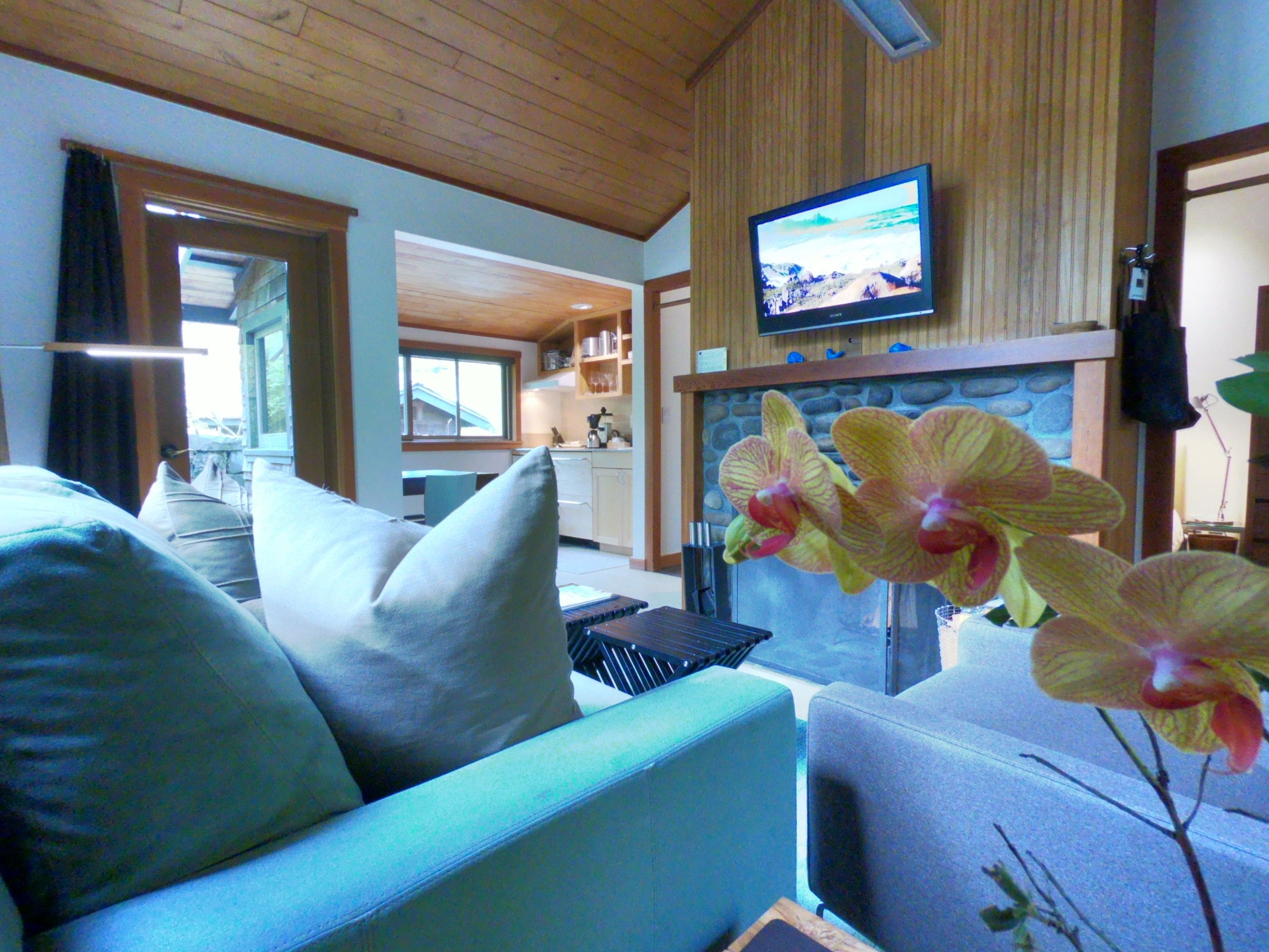 A living room with a sofa, a television mounted on the wall, and a fireplace.