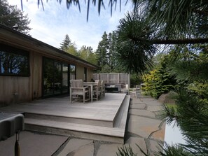 A modern house with a wooden deck, outdoor furniture, and a stone pathway leading to a water feature. - Coast Cabins (Manzanita)