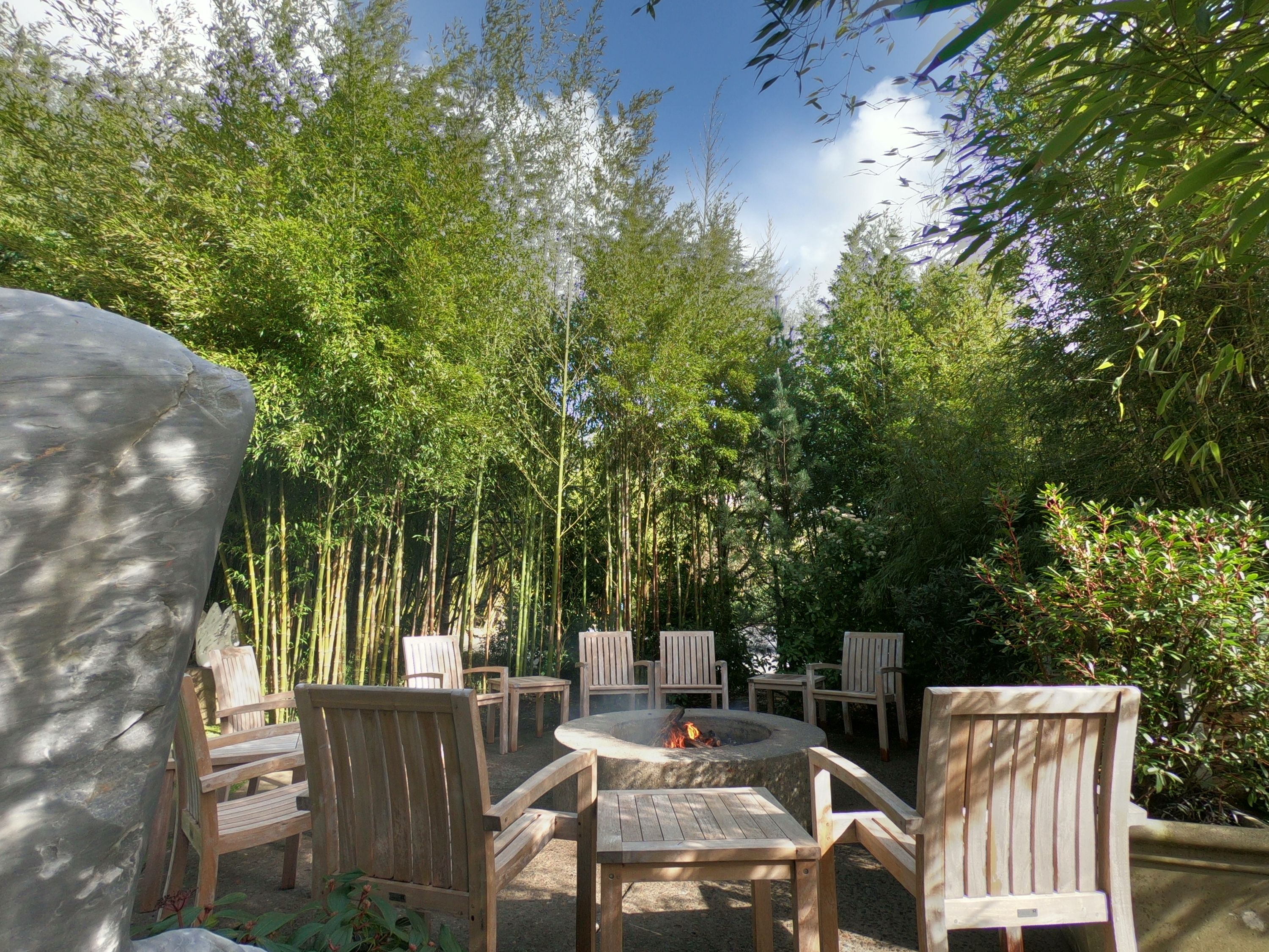 An outdoor seating area with wooden chairs and a fire pit.