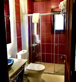 Un baño con inodoro, cabina de ducha y lavamanos.