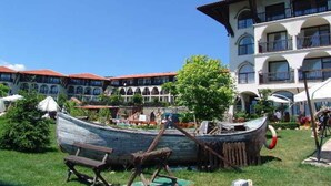 Ein Innenhof mit einem traditionellen Boot, einem Gebäude mit Balkonen und einem strahlend blauen Himmel.