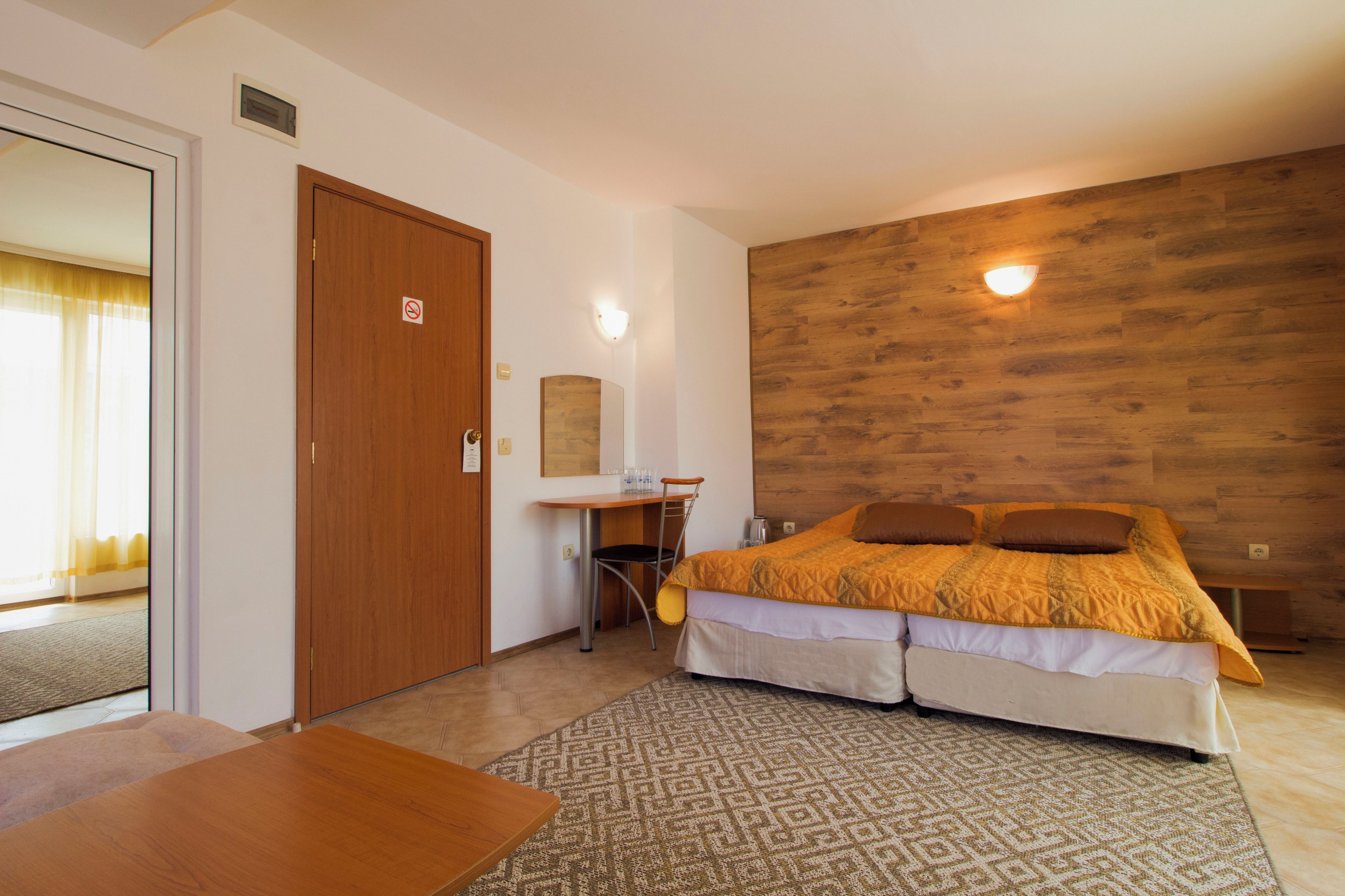 A bedroom with a bed, desk, chair, and a wooden wall.