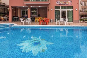 An indoor swimming pool with a tiled floor and a restaurant adjacent to it. - Family Hotel Venera (Nessebar)