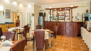 Ein Restaurant mit Bar, Tischen, Stühlen und einem Fliesenboden.