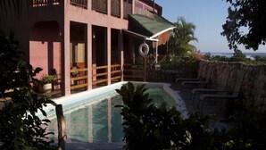 A two-story building with a swimming pool, outdoor seating, and a view of the ocean. - Da Fabio (Negril)