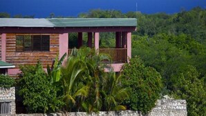 A two-story building with a balcony, surrounded by lush greenery and overlooking a body of water. - Da Fabio (Negril)