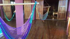 A room with wooden flooring and two hammocks hanging from a wooden beam. - Da Fabio (Negril)